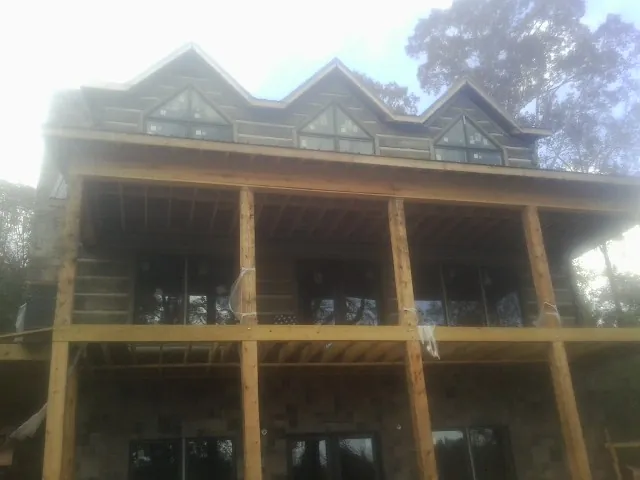 Dormers and porch framing on a large log home under construction — Roof Coating work by our crew in Meade
