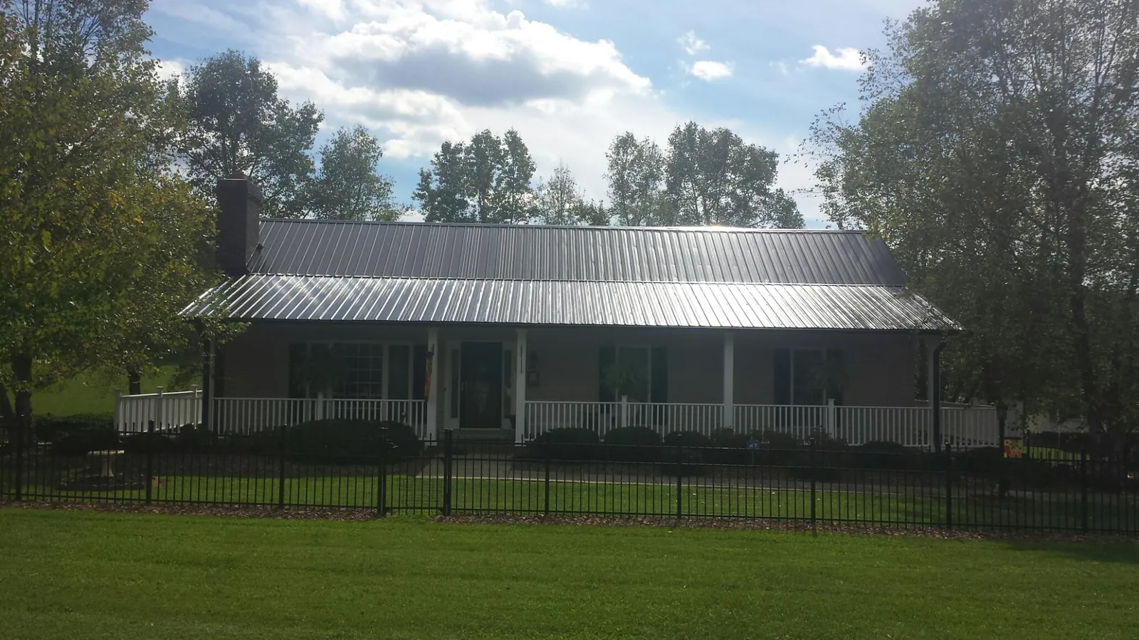 Gray metal roof on a brick ranch with a full width front porch — Gutter Guard Installation work by our crew in Meade