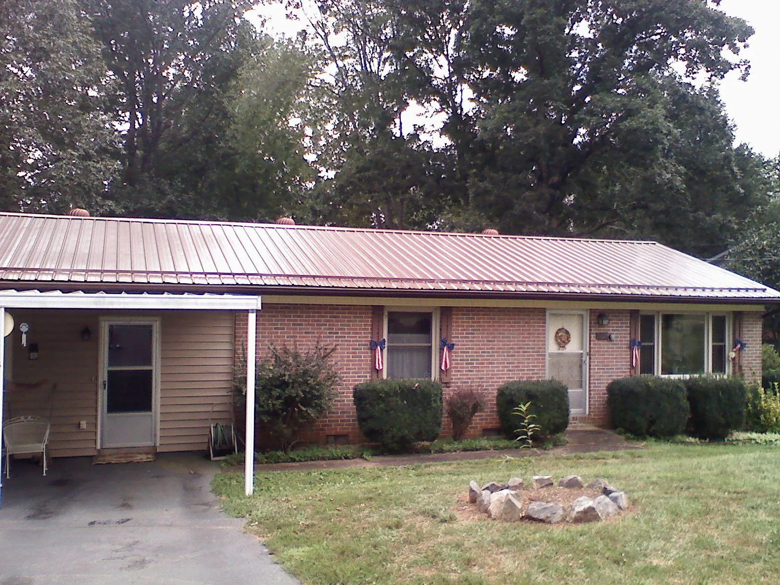 Bronze metal roof and carport on a brick ranch home — Roof Repair work by our crew in Meade