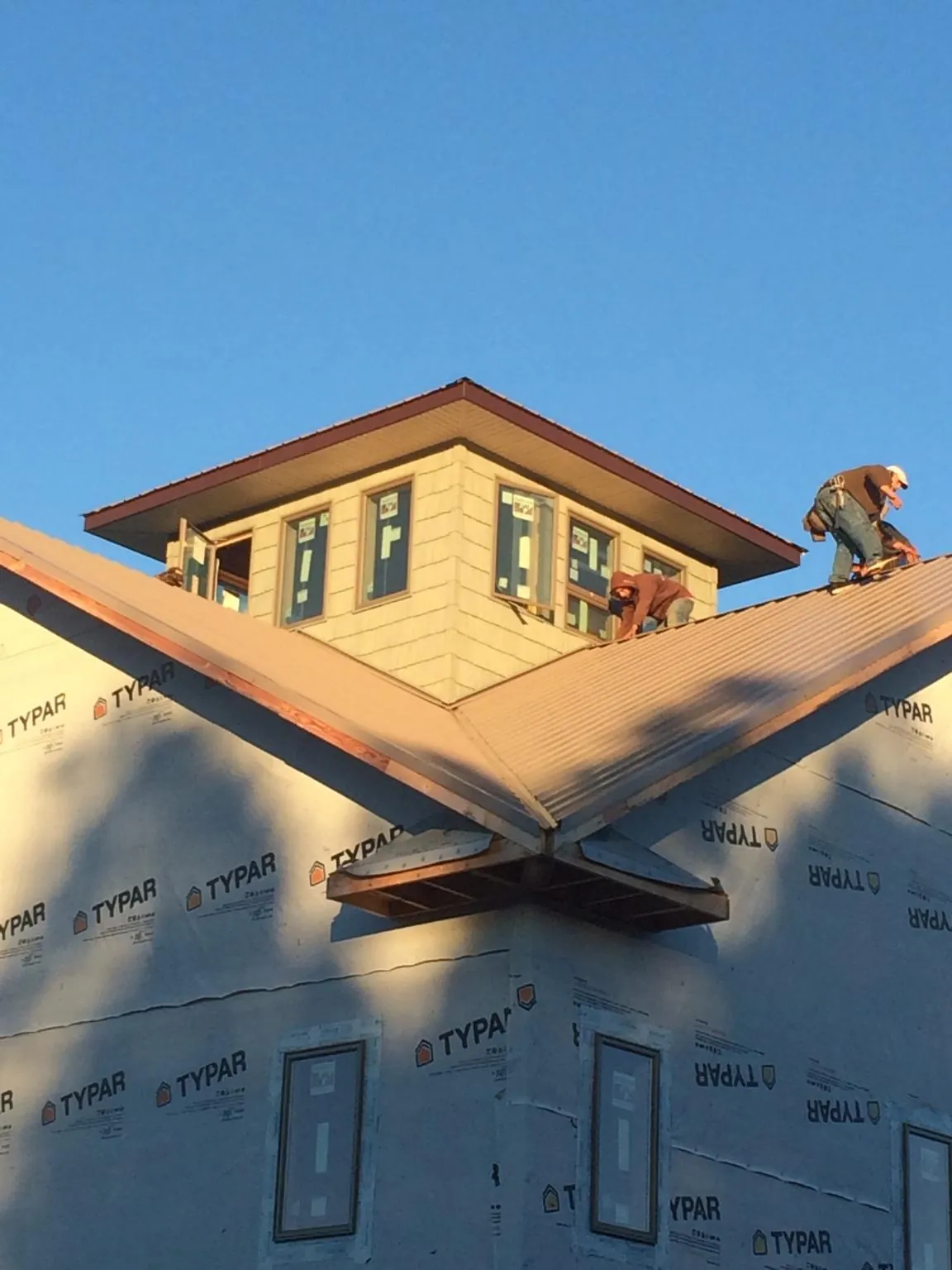 Roofers working around a rooftop cupola on a new metal roof at sunset — Roof Waterproofing in Meade by Roofing Brothers